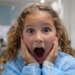 Iznenađeno dete u zubarskoj ordinaciji sa rukama na obrazima