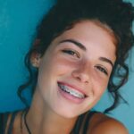 Devojka sa fiksnom protezom koja se smeje ispred plave pozadine